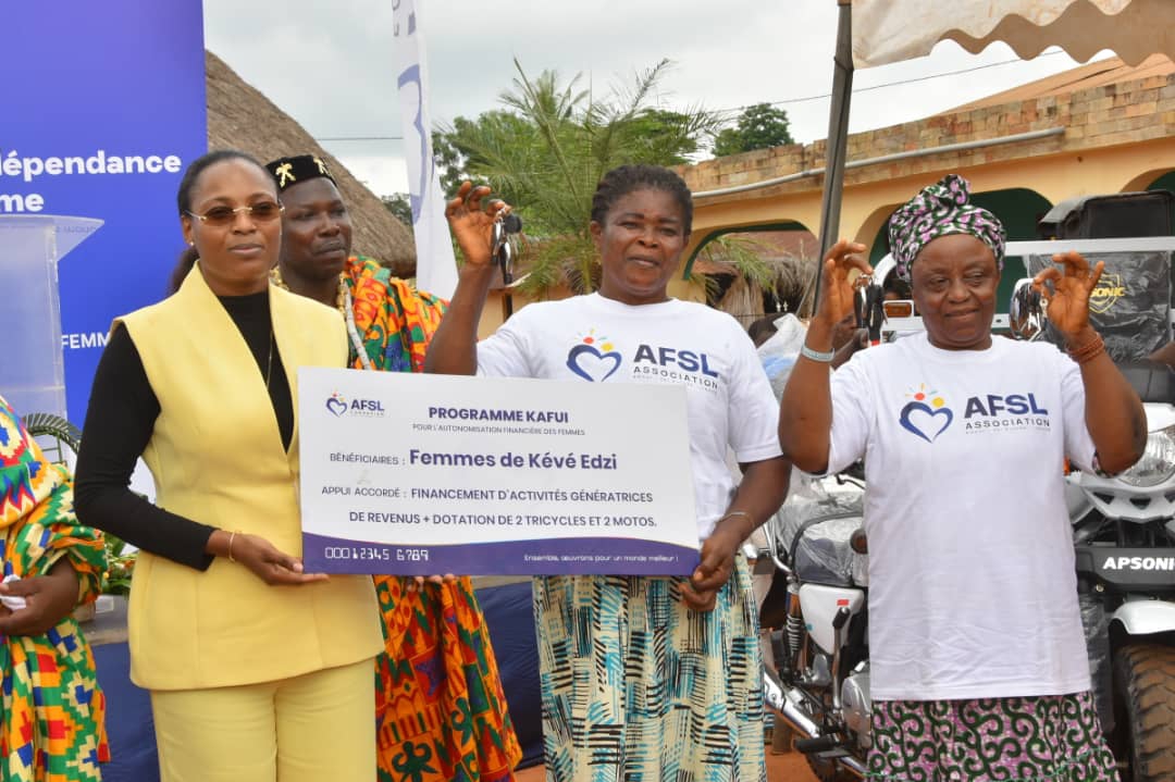 La Présidente de l'AFSL remettant le chèque et les clés des tricycles aux femmes bénéficiaires du Programme KAFUI